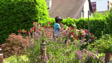 Kadın, parlak güneş ışığında sanal gerçeklik gözlükleriyle bir gül bahçesine hayran ve bitkiler hakkında gerçek zamanlı bilgi ediniyor. VR ve bahçe kavramı.