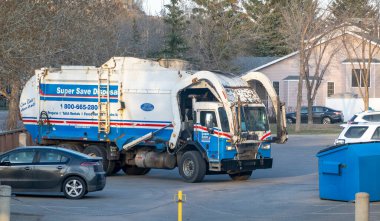 Calgary, Alberta, Kanada. 2 Mayıs 2023. Atık ve geri dönüşüm için bir çöp kamyonu, büyük bir metal mavi çöp kutusunu yüklemek üzere. Konsept: atık imhası