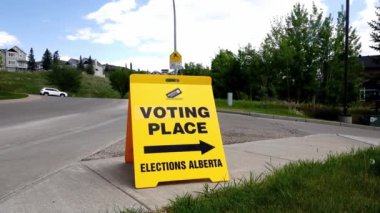 Calgary, Alberta, Kanada. 2 Haziran. 2023. Meşgul bir caddedeki Oy Verme Yeri Alberta tabelasının yan görüntüsü. Sarı çift taraflı zemin standı.