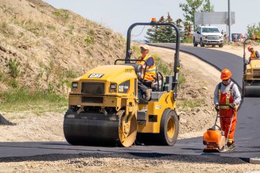 Calgary, Alberta, Kanada. 8 Haziran 2023. Cat Tandem Vibratör kullanan bir inşaat işçisi. Asfalt ya da beton gibi asfalt malzemelerini sıkıştırmak için kullan.