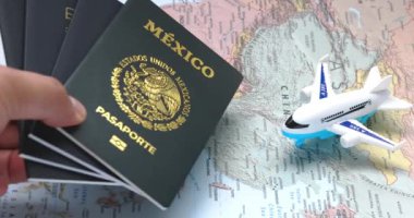 Calgary, Alberta, Kanada. 4 Ağustos 2023. Meksika pasaportunu dünya haritasına bir uçakla bırakan biri. Konsept: Yurtdışına seyahat eden Meksika vatandaşları. 