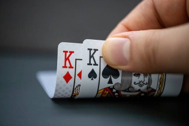 Calgary, Alberta, Kanada. Aralık 18, 2023. Poker oyununda bir çift Kings kartına bakan biri. Canavarlar büyük çiftlerdir..