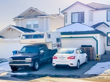 Calgary, Alberta, Kanada. 22 Şubat 2024. Kamyon karavanıyla donatılmış bir kamyonet kış mevsiminde bir konut garajının önüne park edilmiş..