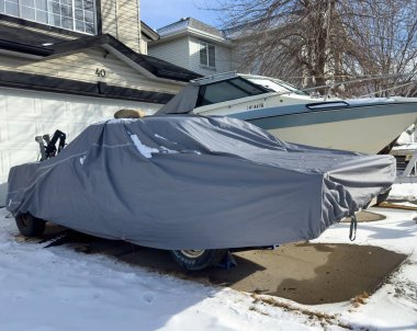 Calgary, Alberta, Kanada. 29 Şubat 2024. Garajın dışındaki kar yığınından korunmak için gümüş rengi hava geçirmez bir arabası olan bir araç..