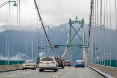 Vancouver, British Columbia, Kanada. 12 Nisan 2024. Yağmurlu bir günde, kalabalık trafiğin ortasında araçlarla Lions Gate Köprüsü..