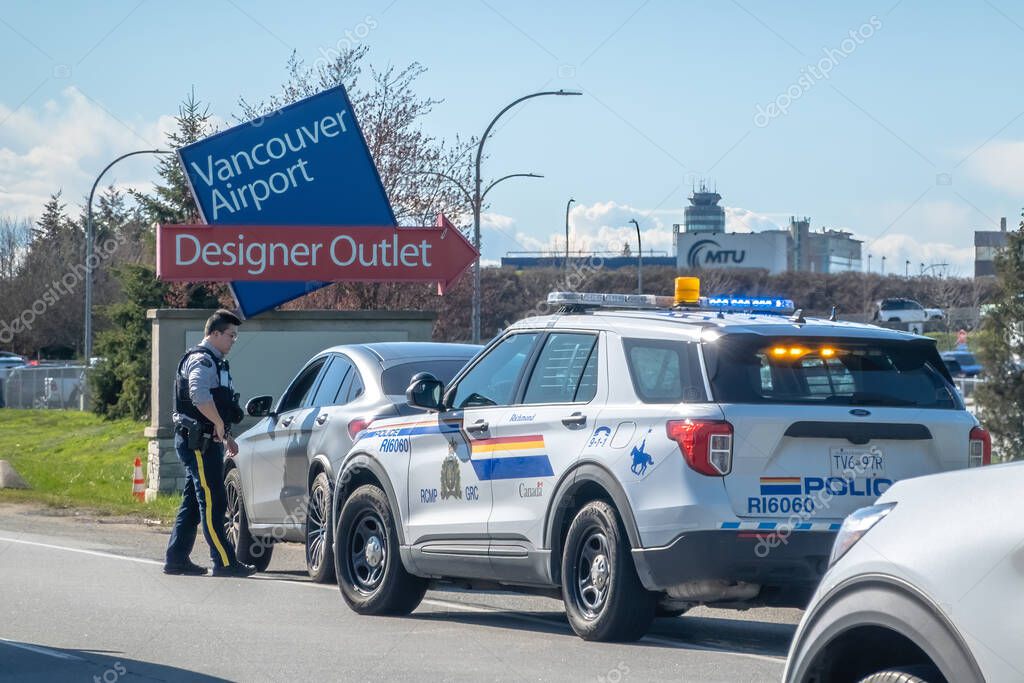 Vancouver, British Columbia, Canada. Apr 6, 2024. An RCMP or Royal Canadian Mounted Police officer stopping a civilian at the Vancouver Airport.