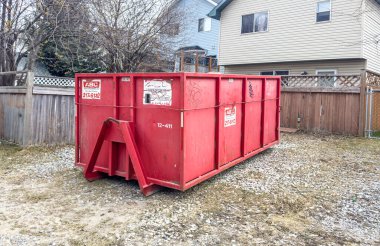 Calgary, Alberta, Kanada. 2 Mayıs 2024. Tadilat yapılan bir konutun arka bahçesinde bulunan kırmızı bir çöp bidonu..