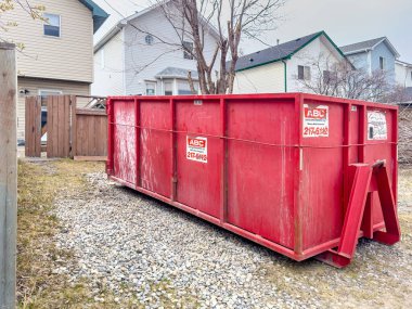 Calgary, Alberta, Kanada. 2 Mayıs 2024. Şu anda tadilat yapılan bir konutun arkasında kırmızı bir atık konteynırı bulunuyor..