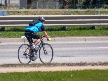 Calgary, Alberta, Kanada. 14 Mayıs 2024. Bir bisikletçi bahar sezonunda yol kenarında geziniyor..