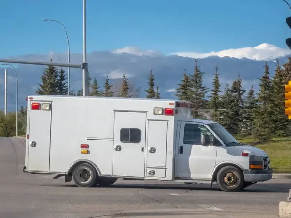 stock image A side view of a plain white ambulance traveling on the road.