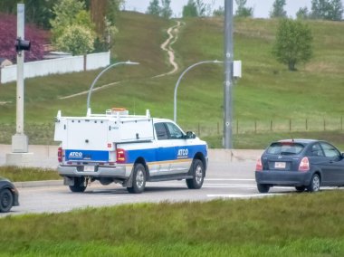 Calgary, Alberta, Kanada. 5 Haziran 2024. Üzerinde ATCO logosu olan mavi-beyaz bir kamyonet baharda yeşil ağaçlar ve tepelerle otoyolda ilerliyor..