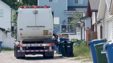 Calgary, Alberta, Kanada. 14 Haziran 2024. Mekanik kolu olan Calgary şehri arka sokaktaki mavi geri dönüşüm kutusunu boşaltıyor..