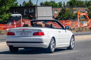Calgary, Alberta, Kanada. 25 Haziran 2024. Üstü açık, siyah üstü açık bir araba. Şehir caddesinde inşaat alanının yanında. 2001 BMW 325Ci, popüler iki kapılı model bir araç..