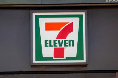 Calgary, Alberta, Kanada. 25 Haziran 2024. Gri duvarlı bir mağazanın dış tarafına 7-Eleven tabelası asılmış..