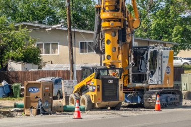 Calgary, AB, Kanada. 25 Haziran 2024. Sarı bir buldozer ve metal patlamalı büyük bir vincin yer aldığı hareketli bir inşaat alanı..