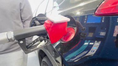 Calgary, Alberta, Kanada. 23 Haziran 2024. Bir benzin istasyonundaki siyah bir arabanın yakıt deposuna kırmızı yakıt hortumu sokuluyor..