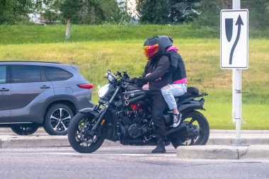 Calgary, Alberta, Kanada. Haziran 01, 2024. Yamaha motosikleti süren iki kişi. Her ikisi de kask ve siyah ceket giyiyor..