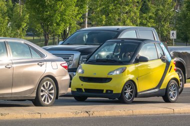 Calgary, Alberta, Kanada. 12 Temmuz 2024. Sarı bir Smart. İki kişilik küçük bir araba trafikte durdu..