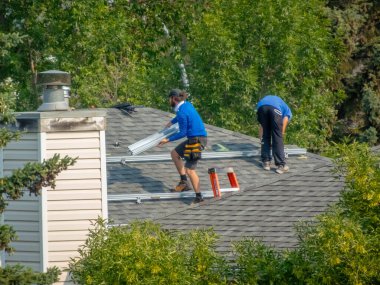 Calgary, Alberta, Kanada. 17 Haziran 2024. Bir evin çatısına güneş panelleri kuran bir çift işçi..