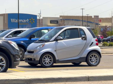 Calgary, Alberta, Kanada. 17 Haziran 2024. İki kişilik gümüş rengi bir Smart Walmart mağazasının önüne park edilmiş küçük bir araba..