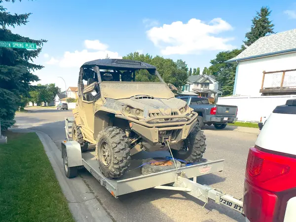 stock image Calgary, Alberta, Canada. Jul 15, 2024. A muddy Can-Am Maverick X3 side-by-side is parked on a trailer in front of a house parked on the street.