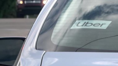 Calgary, Alberta, Kanada. 20 Haziran 2024. Bir arabanın arka camındaki Uber araç etiketinin yakın çekimi, Uber arabası durdurulurken trafik geçiyor..