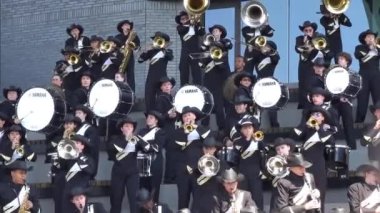 Calgary, Alberta, Kanada. 17 Haziran 2024. Siyah beyaz üniformalar ve kovboy şapkaları giyen bando bandosu, katlı tribünlerde enerjik bir performans sergiliyor. Müzisyenler pirinç, ahşap rüzgar ve perküsyon çalar..