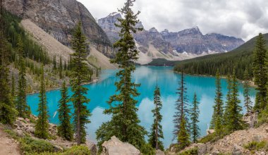 Banff Ulusal Parkı 'ndaki Moraine Gölü' nün nefes kesici manzarası canlı turkuaz sularını, yüksek dağ zirvelerini ve yemyeşil ormanları gözler önüne seriyor..
