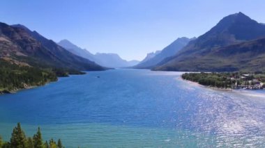 Kanada 'nın Waterton Gölü' nün sakin manzarası, yükselen dağlar ve el değmemiş mavi sular tarafından çerçevelenmiş, temiz bir gökyüzü altında doğanın sükunetini yansıtıyor..