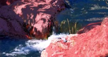 Kanada, Alberta 'daki Red Rock Canyon Parkway' in pitoresk bir sahnesinde canlı kırmızı kaya oluşumları ve çağlayan şelaleler yemyeşil bir manzaranın ortasında sergileniyor..