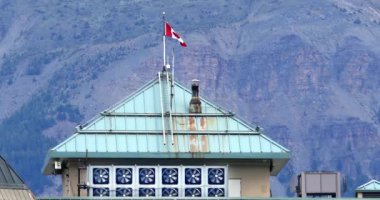 Louise Gölü, AB, Kanada. 27 Ağustos 2024. Fairmont Şatosu Louise Gölü 'nün mercan çatısı ve havalandırma sistemi Kanada bayrağıyla görkemli dağların önünde gururla dalgalanır.. 