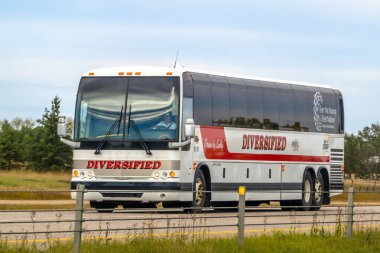 Red Deer, Alberta, Canada. Sep 29, 2024. A Diversified coach bus is seen traveling on a highway, marked with the Fort McMurray First Nation Group of Companies logo on its side. clipart