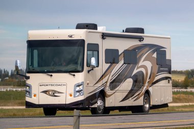 Calgary, Alberta, Kanada. 2 Ekim 2024. Bej renkli spor bir karavan otoyolda sürüyor, parlak tasarımını kahverengi ve siyah grafiklerle dinamik girdaplarla sergiliyor..