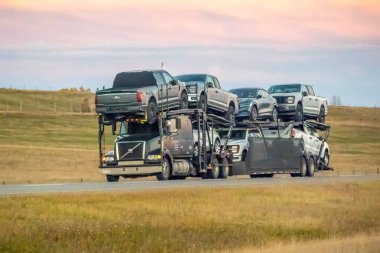 Calgary, Alberta, Kanada. 25 Ekim 2024. Büyük bir nakliye kamyonu çeşitli araçlar, çok katlı bir taşıyıcıyla otobanda taşımaktadır..