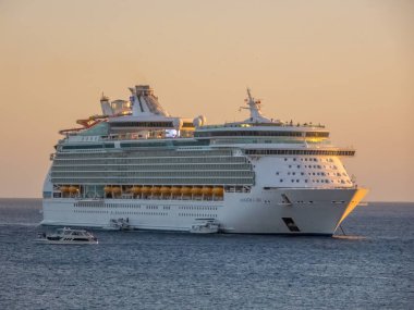 Los Cabos, B.C.S., Meksika. 28 Kasım 2024. Batan güneşin sıcacık parıltısıyla aydınlanan görkemli bir yolcu gemisi okyanusun sakin sularında süzülüyor..