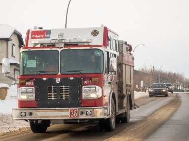 Calgary, Alberta, Kanada. 9 Aralık 2024. Kırmızı Calgary İtfaiye Departmanı 'nın ışıkları yanıp sönen kamyonu karlı bir yolda ilerliyor..
