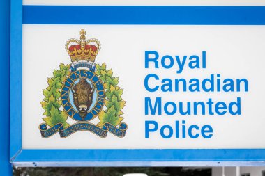 Banff, Alberta, Kanada. Aralık 19, 2024. Kanada Kraliyet Atlı Polisi bayrağına yakın çekim. RCMP 'nin arması, taç, akçaağaç yaprağı ve bizon içeren bir tabela üzerinde sergileniyordu..