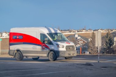 Calgary, Alberta, Kanada. 18 Ocak 2025. Beyaz bir Canada Post minibüsü şehir caddesi boyunca posta ve paket taşır..
