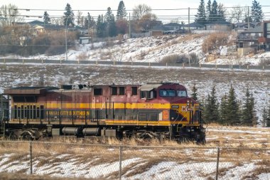 Calgary, Alberta, Kanada. 18 Ocak 2025. Kansas City 'nin güneyli bir yük treni kışı geçirmek üzere. Lokomotif, şirketin imzasıyla kırmızı ve sarıya boyanmış..