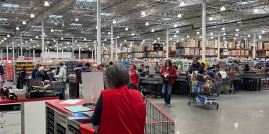 Calgary, Alberta, Kanada. 18 Ocak 2025. Bir Costco toptan satış mağazasında müşteriler, çeşitli ürünlerle dolu uzun raflarla çerçevelenmiş eşyalar ile kuyrukta bekliyorlar..