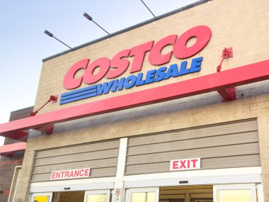 Calgary, Alberta, Kanada. 24 Ocak 2025. İkonik kırmızı ve mavi logolu bir Costco toptancısı girişi. Binanın tuğla bir cephesi ve giriş ve çıkış işaretleri olan büyük bir tentesi var..
