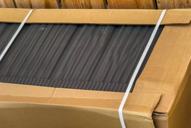 Bükülmüş bir metal çatı, dayanıklılığını ve kayma direncini gösteriyor. Hala orijinal kutunun içinde..