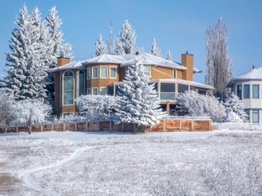 Calgary, Alberta, Kanada. 2 Şubat 2025. Evler, karlı bir kış manzarasında yuva yapar. Sıcak tonları, el değmemiş beyaz ile çelişir..