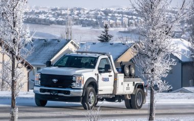 Calgary, Alberta, Kanada. 2 Şubat 2025. Beyaz bir Ford F-450 Super Duty çekici, AMA logosu karlı bir iskan caddesinde duruyor, kışın yol yardımını gösteriyor..