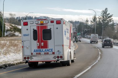 Victoria, British Columbia, Kanada. 10 Şubat 2025. BC Ambulans Aracı 'nın arka görüntüsü, karlı bir yolda acil durum ışıkları yanıp sönerken acil servislerin hayati önemini vurguluyor..
