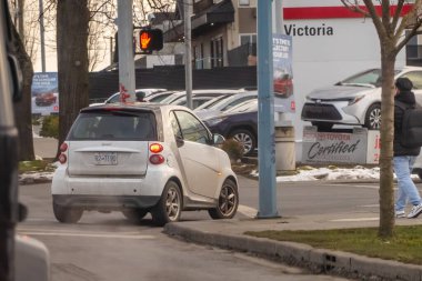 Victoria, British Columbia, Kanada. 10 Şubat 2025. White Smart Fortwo EV Victoria, BC 'de bir şehir caddesinde sürüyor, şehir ulaşımını ve elektrikli araçları vurguluyor.