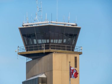 Calgary, Alberta, Kanada. 10 Şubat 2025. Kanada bayrağı taşıyan Calgary Havalimanı (YYC) eski kontrol kulesi, açık mavi gökyüzüne karşı hava trafik yönetimi ve Kanada havacılığını vurguluyor.