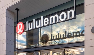Victoria, British Columbia, Kanada. 14 Şubat 2025. Lululemon mağaza önü belirgin bir logo ve açık tabela bir ışık taşı ön cephe, gökyüzünü yansıtan ve cam ağaçlar.