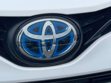 Victoria, British Columbia, Kanada. 14 Şubat 2025. Toyota logosu, gümüş ve maviyle kenetlenmiş ikonik ovaller, hibrit bir aracın beyaz üzerine monte edilmiş..