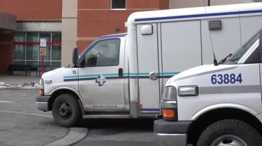 Victoria, British Columbia, Kanada. 12 Şubat 2025. Beyaz bir Medi-Van ambulansı kırmızı tuğlalı ve büyük camlı pencereli Royal Jubilee Hastanesi Acil Servis binasının önünden geçiyor.. 